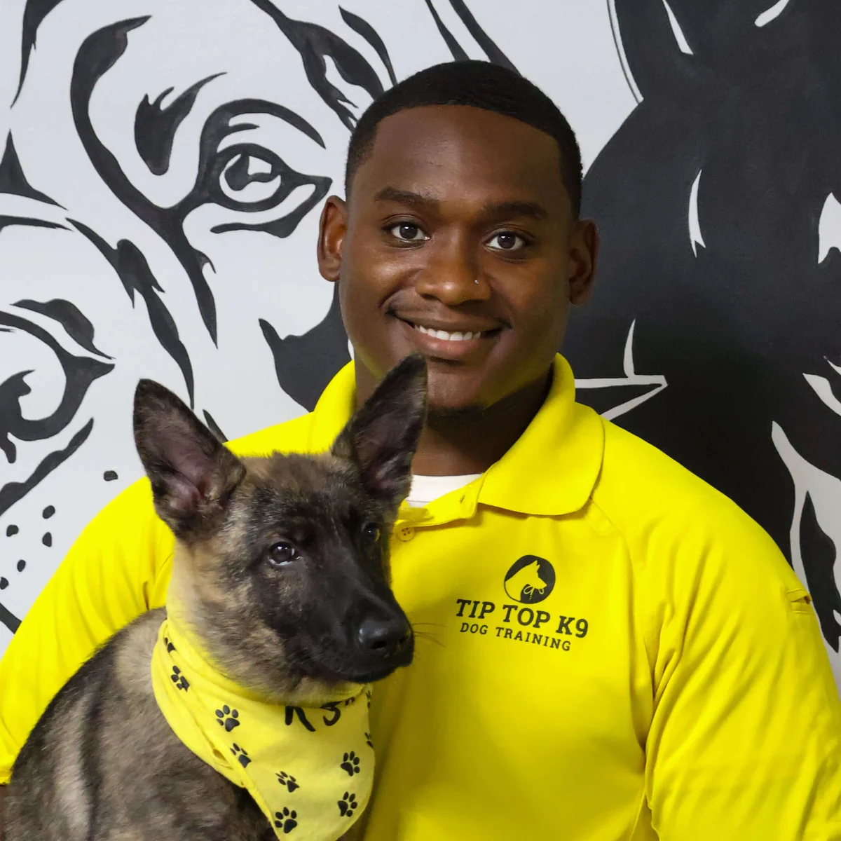 Ahmad Bradshaw, owner and lead trainer at Tip Top K9 Humble, holding a young Belgian Malinois puppy